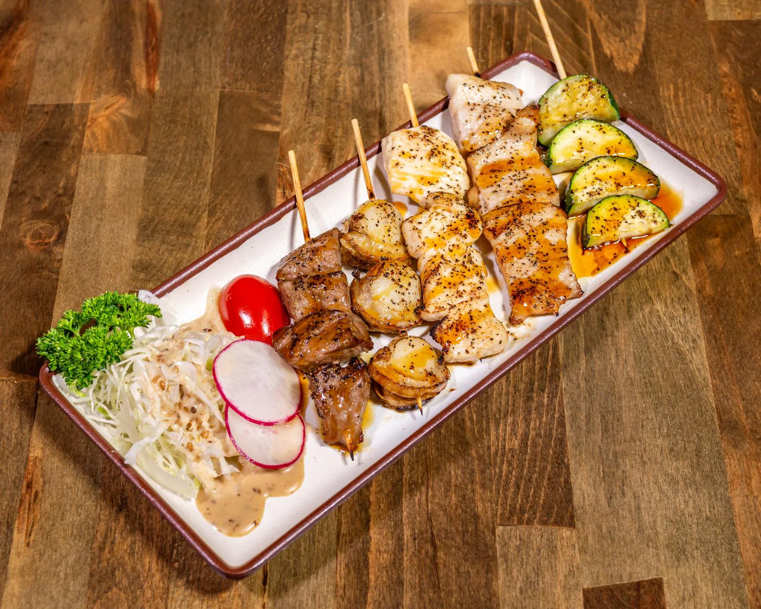 Yakitori Platter with grilled beef, scallop, chicken, and zucchini skewers served alongside slaw, radish, and tomato